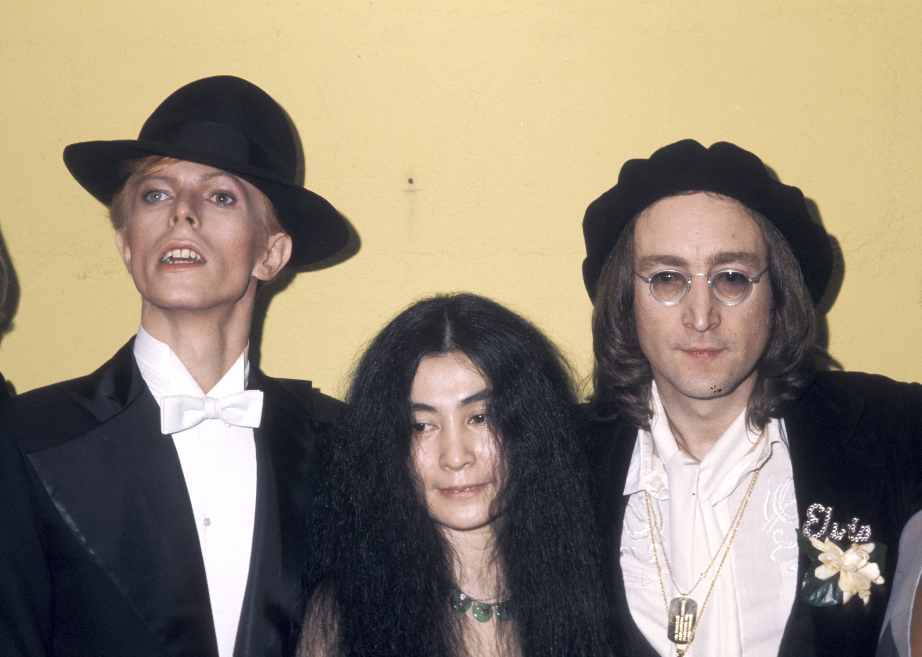 David Bowie, Yoko Ono, and John Lennon in front of a wall