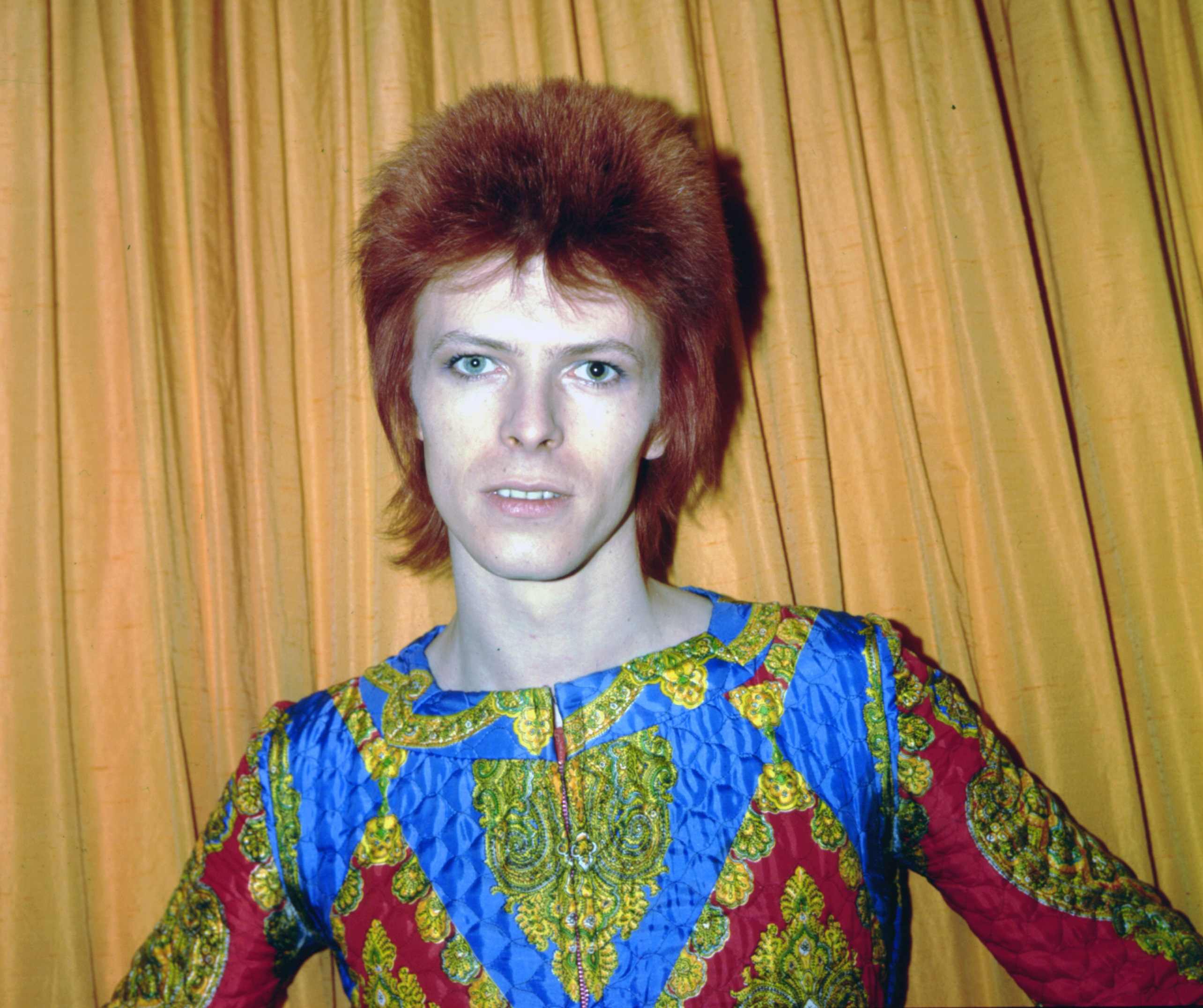 David Bowie as Ziggy Stardust in front of a curtain