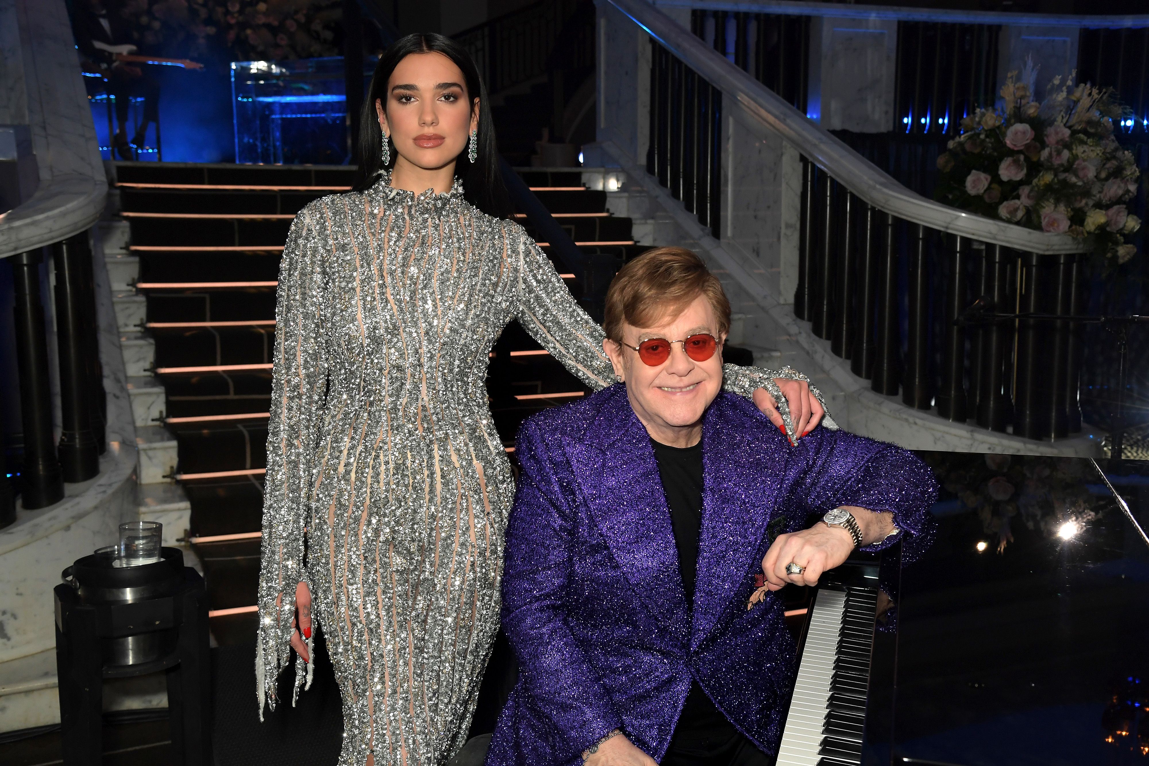 Dua Lipa putting her arm around Elton John