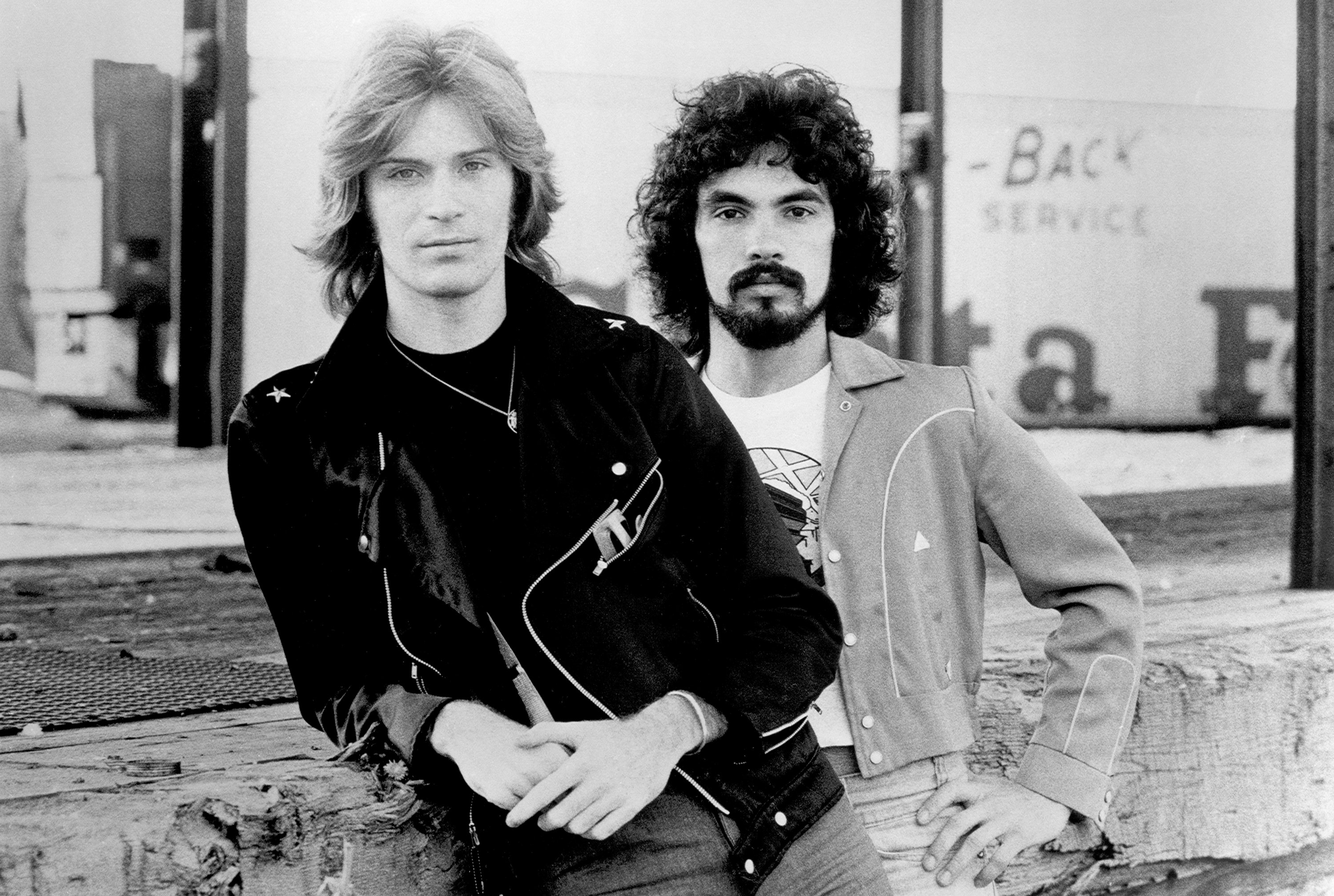 Daryl Hall and John Oates leaning on some wood