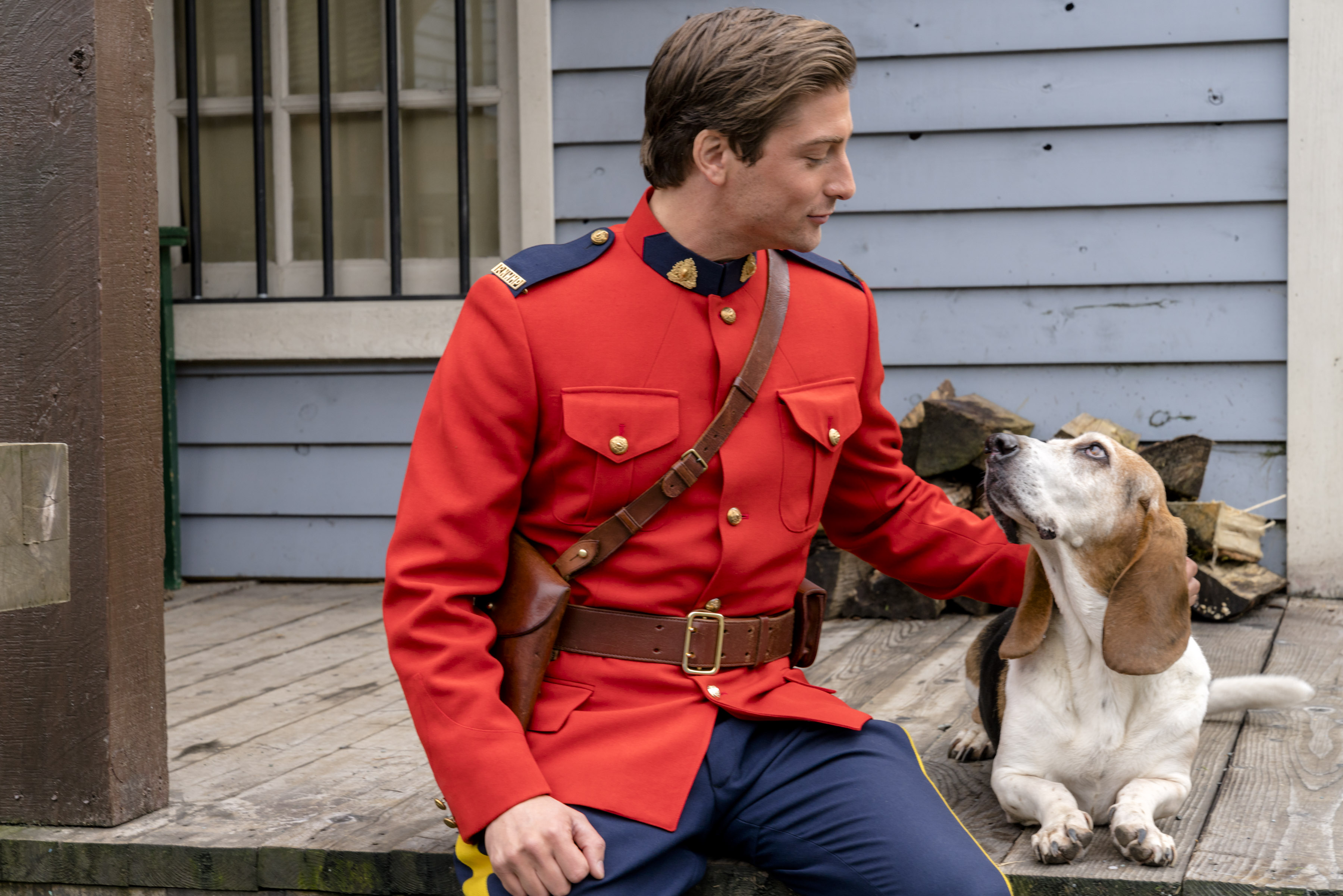 Jack, in a red jacket, petting a dog in an episode of 'When Calls the Heart'
