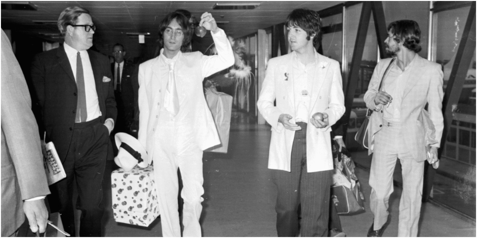 John Lennon and Paul McCartney both dressed in white and carrying apples to promote their new company Apple Corps.