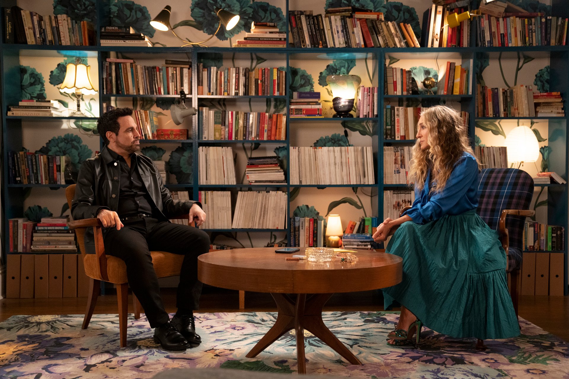 Mario Cantone and Sarah Jessica Parker sit in Carrie's apartment during a scene in 'And Just Like That...'