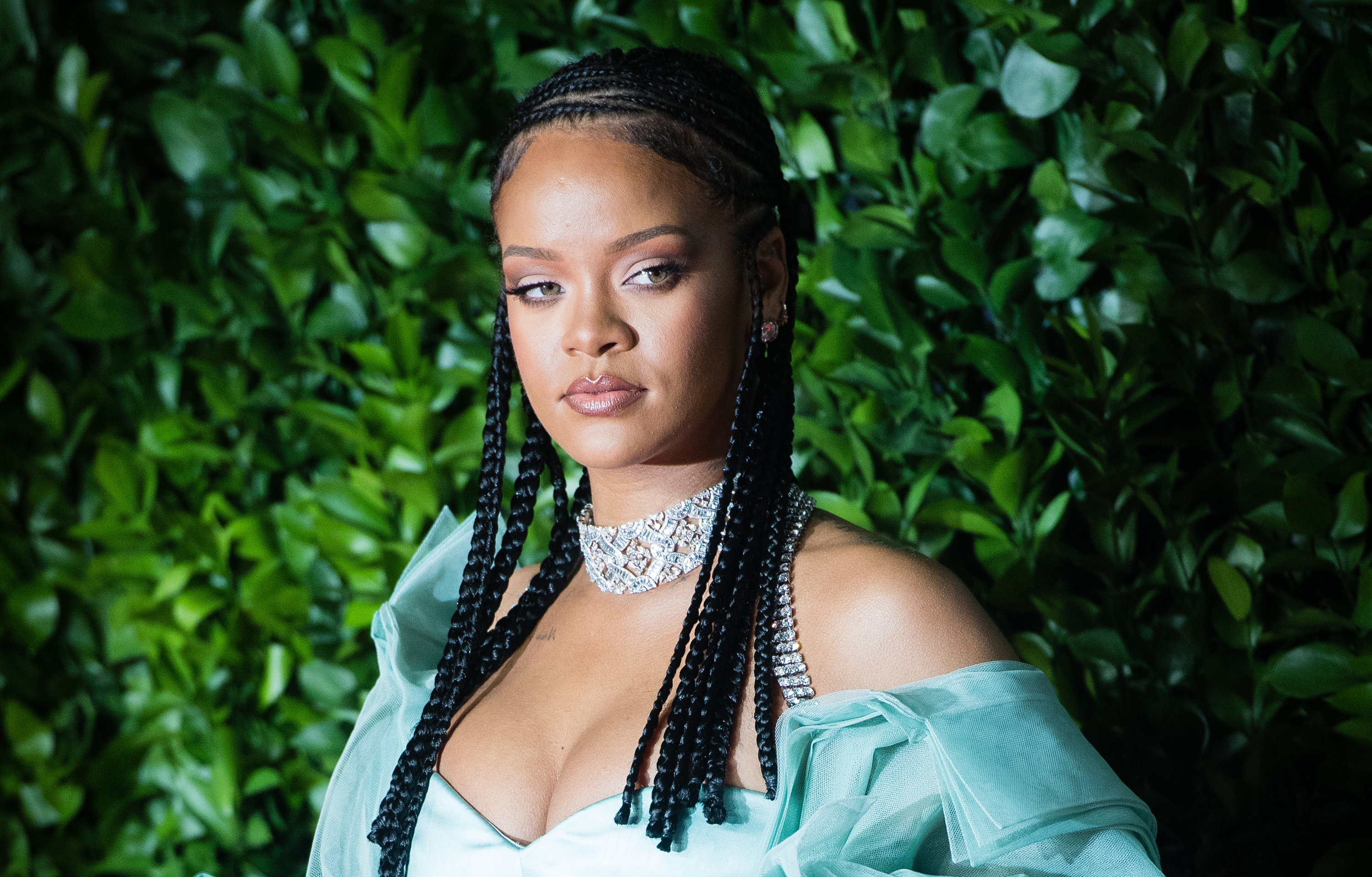 Rihanna in front of a green plant