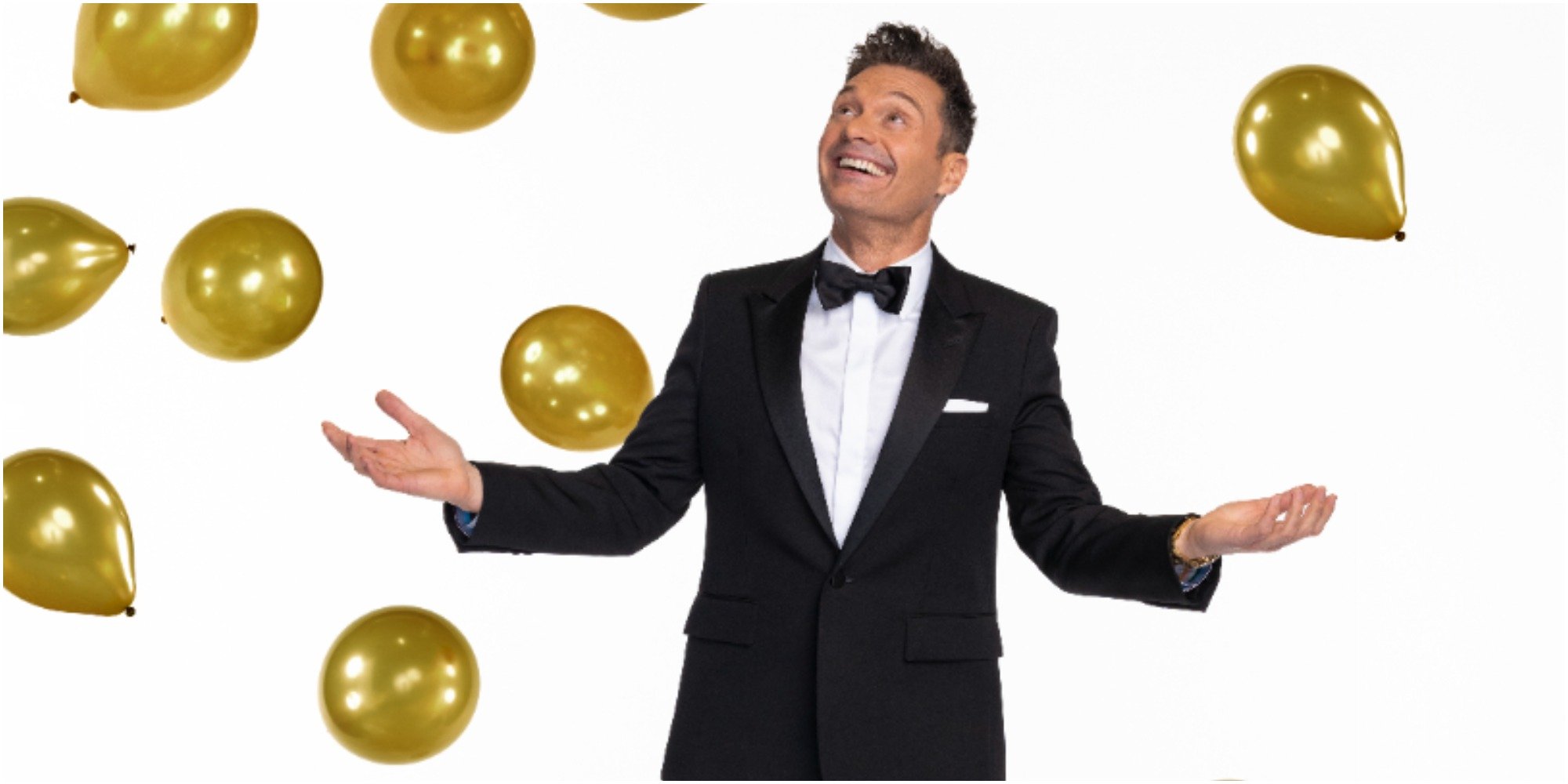 Ryan Seacrest with gold balloons surrounding him.