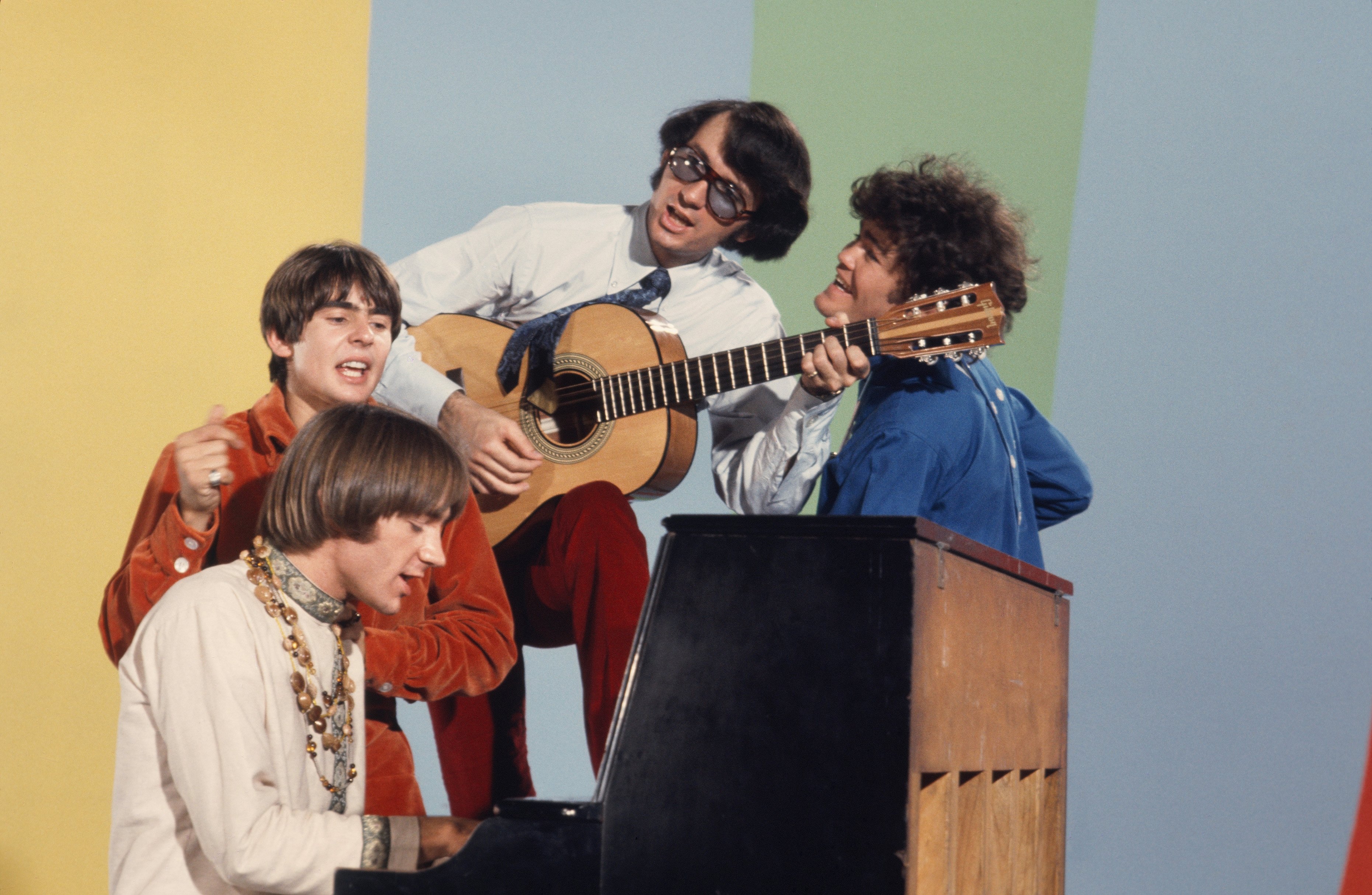 The Monkees' Davy Jones, Peter Tork, Mike Nesmith, and Mickey Dolenz at a piano