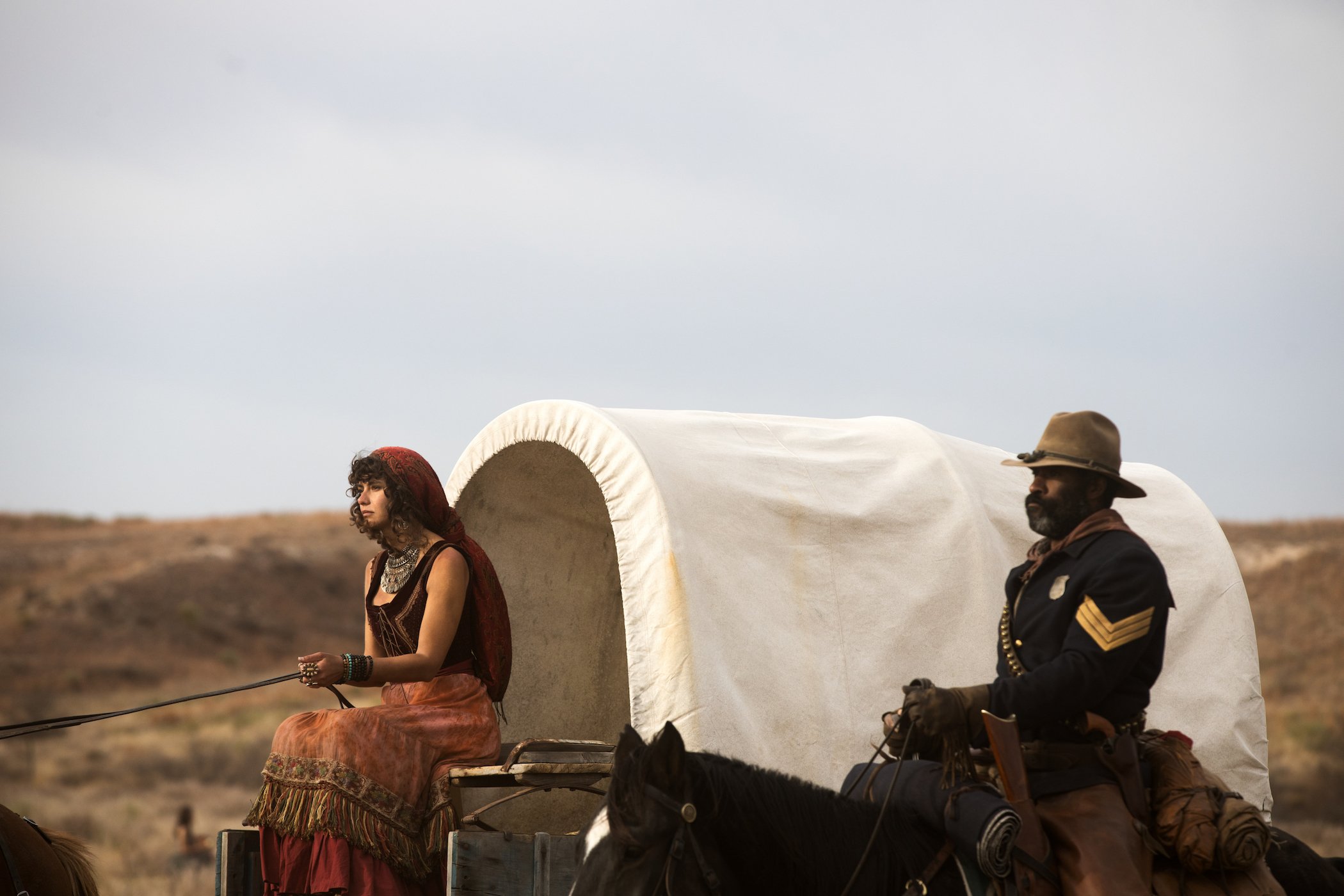 Gratiela Brancusi as Noemi and LaMonica Garrett as Thomas riding wagons next to each other in '1883'