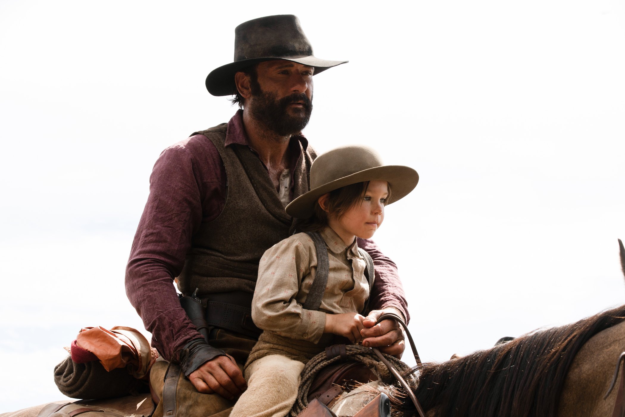 Tim McGraw as James Dutton riding a horse with a child sitting in front of him in '1883'