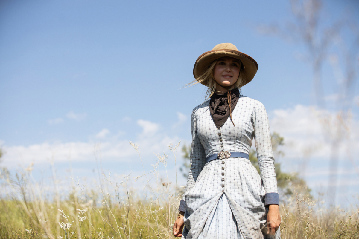 Isabel May as Elsa in a blue dress alone in a field in '1883'