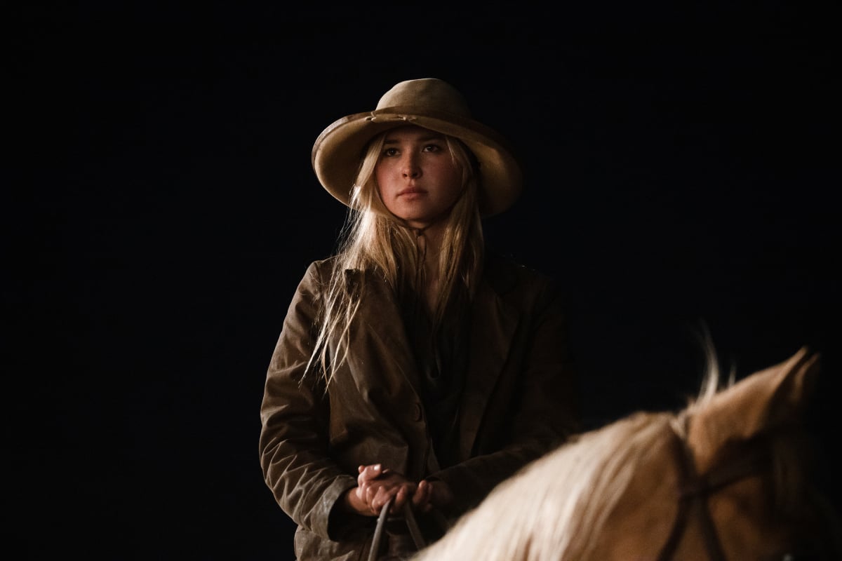 Isabel May as Elsa of the Paramount+ original series 1883. Elsa wears a hat and jacket and rides a horse.