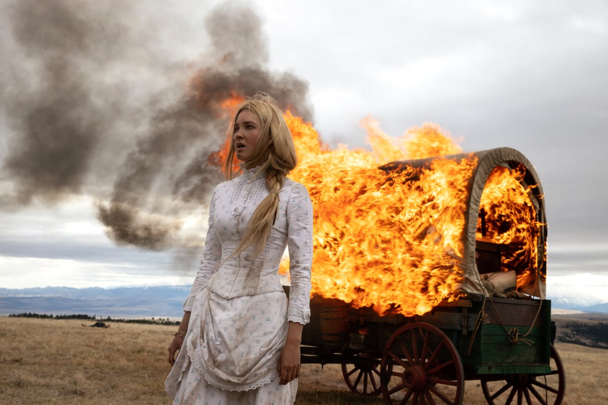 Isabel May as Elsa of the Paramount+ original series 1883. Elsa stands in front of a burning wagon.