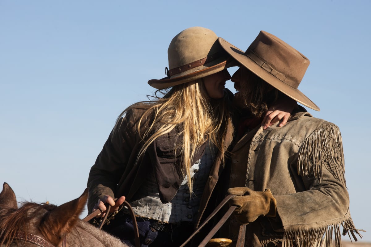 Isabel May as Elsa and Eric Nelsen as Ennis of the Paramount+ original series 1883. Elsa and Ennis are on horses and about to kiss.