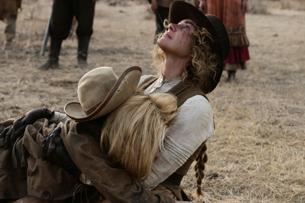 Faith Hill as Margaret and Isabel May as Elsa of the Paramount+ original series 1883. Elsa sobs in Margaret's arms. 3