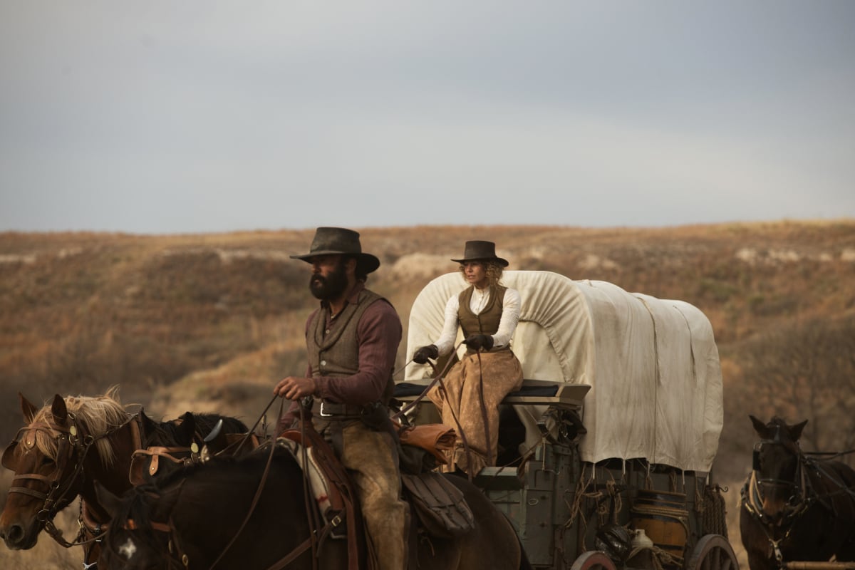 Tim McGraw as James and Faith Hill as Margaret in the Paramount+ original series '1883.' Margaret rides in front of a covered wagon, and James rides a horse in front.