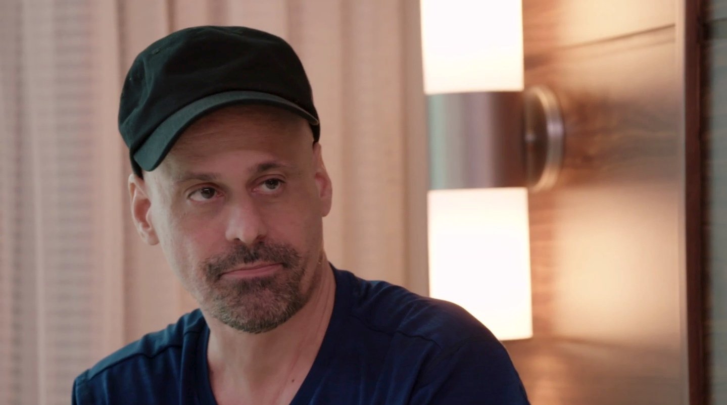 'Before the 90 Days' Season 5 star Gino sitting on a bed with a black t-shirt and hat.