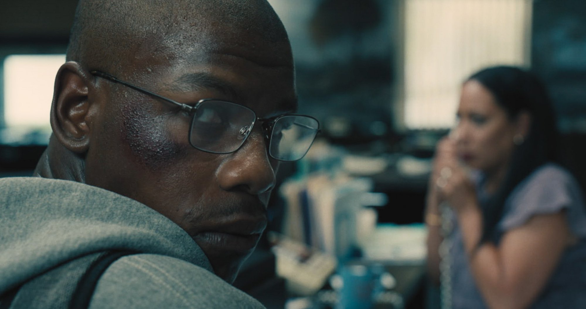 '892' John Boyega as Brian Brown-Easley wearing glasses and a grey hoodie