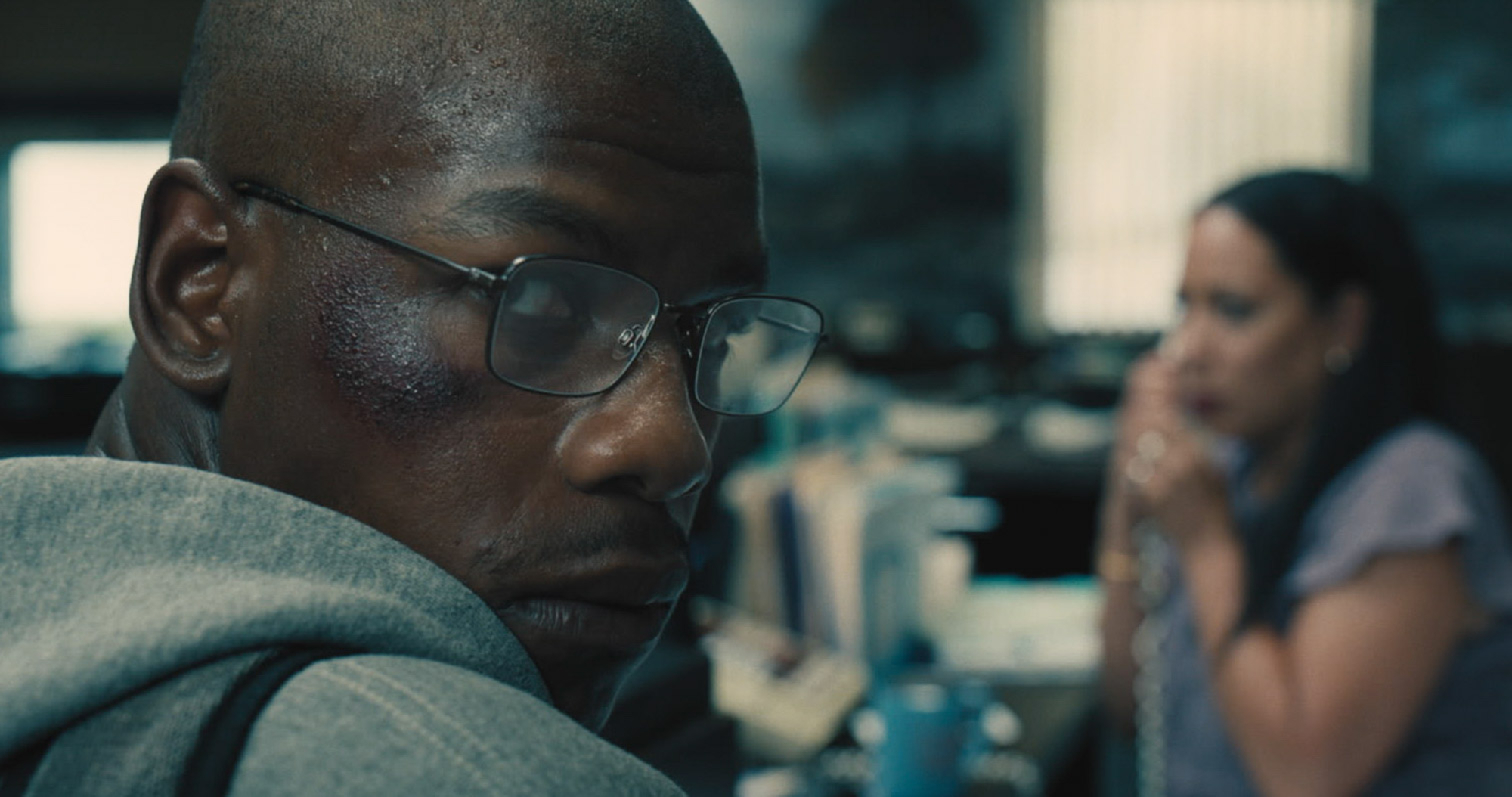 '892' John Boyega as Brian Brown-Easley wearing glasses and a grey hoodie