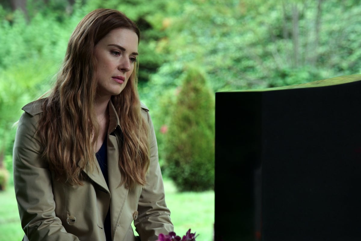 Alexandra Breckenridge as Melinda Monroe wearing an olive jacket and kneeling in front of a headstone in 'Virgin River