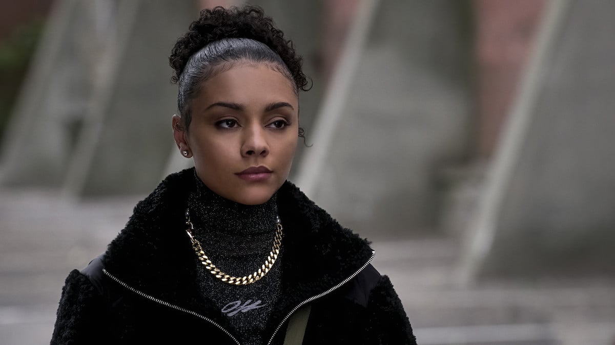 Alix Lapri as Effie Morales wearing a curly bun black jacket and a gold chainon 'Power Book II: Ghost'