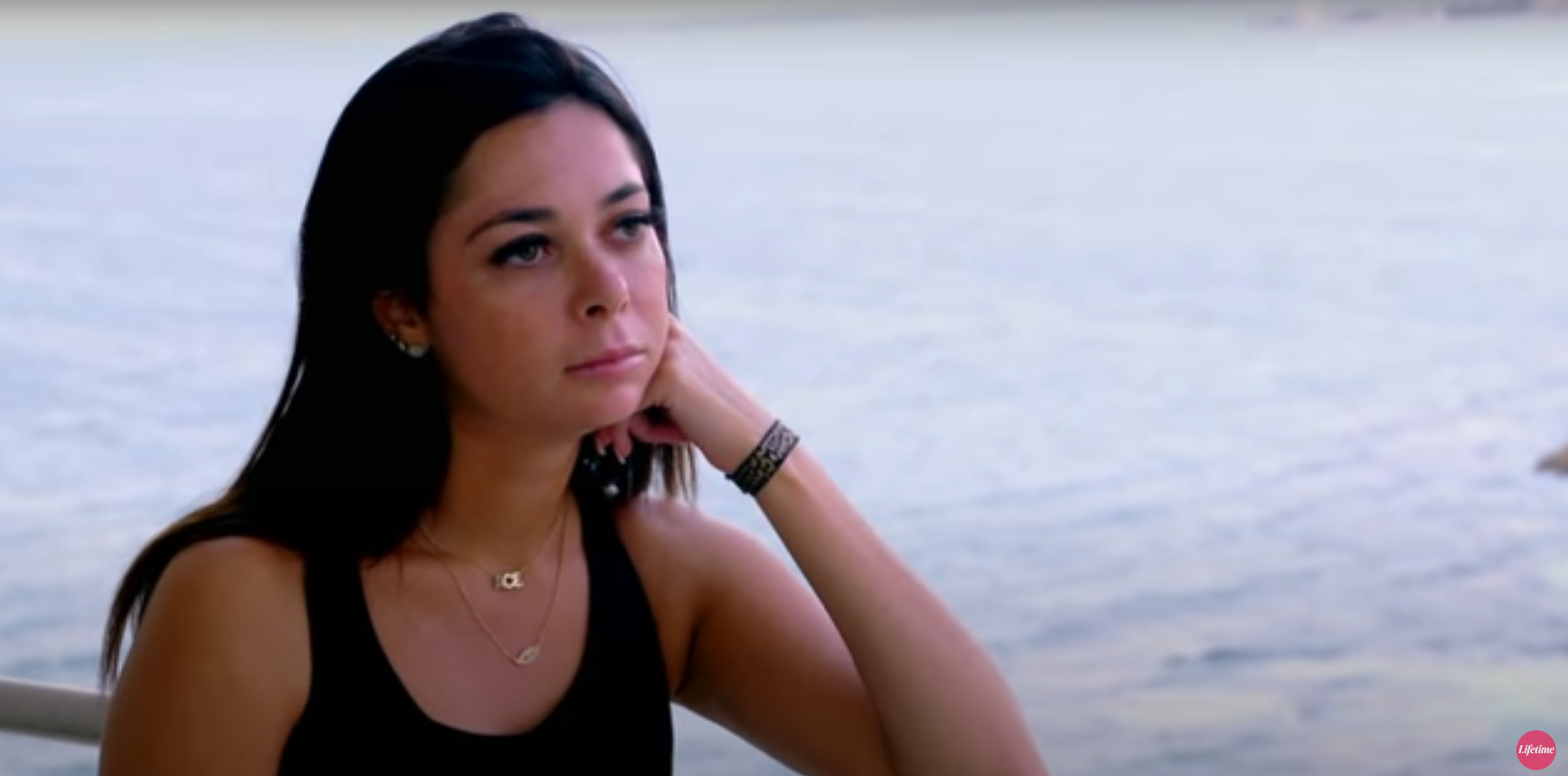 Alyssa, hand on chin and standing on a balcony in front of the ocean, in an episode of 'Married at First Sight'