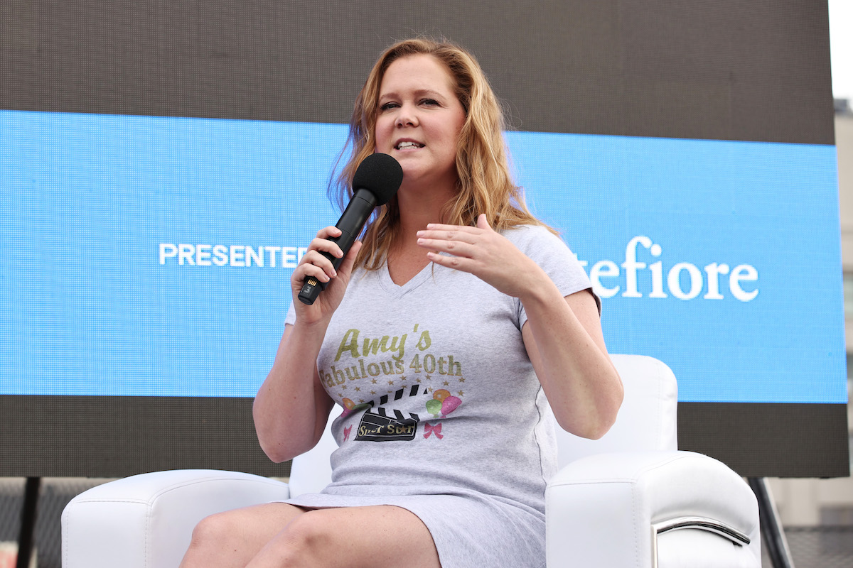 Amy Schumer speaks into a microphone while seated on stage.