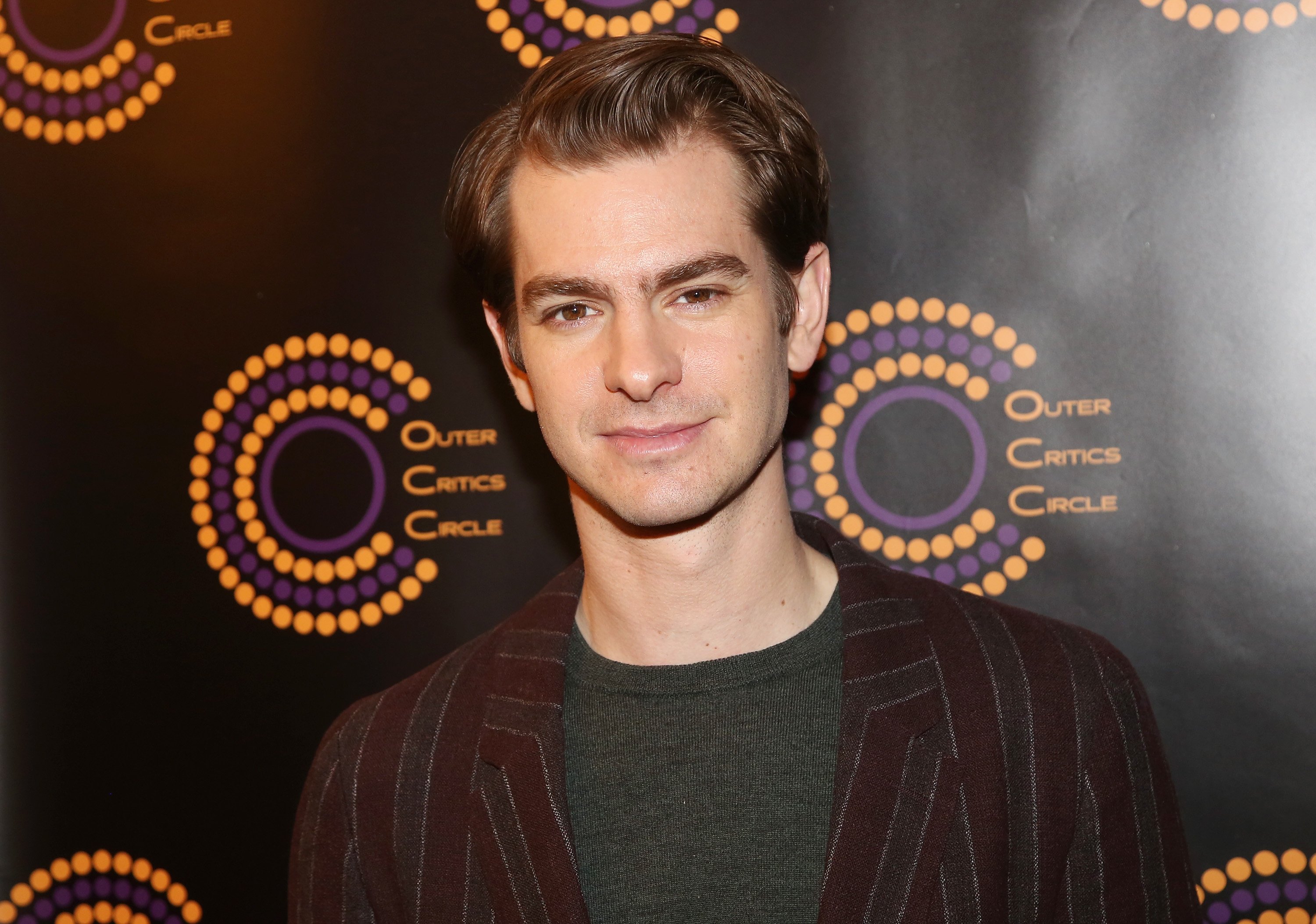 'Spider-Man: No Way Home' star Andrew Garfield wears a dark red and gray striped blazer over a gray shirt.