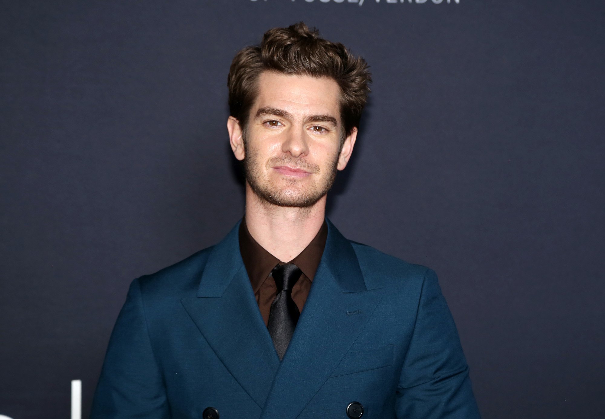 'Spider-Man: No Way Home' actor Andrew Garfield wearing a blue suit, brown shirt, and black tie.