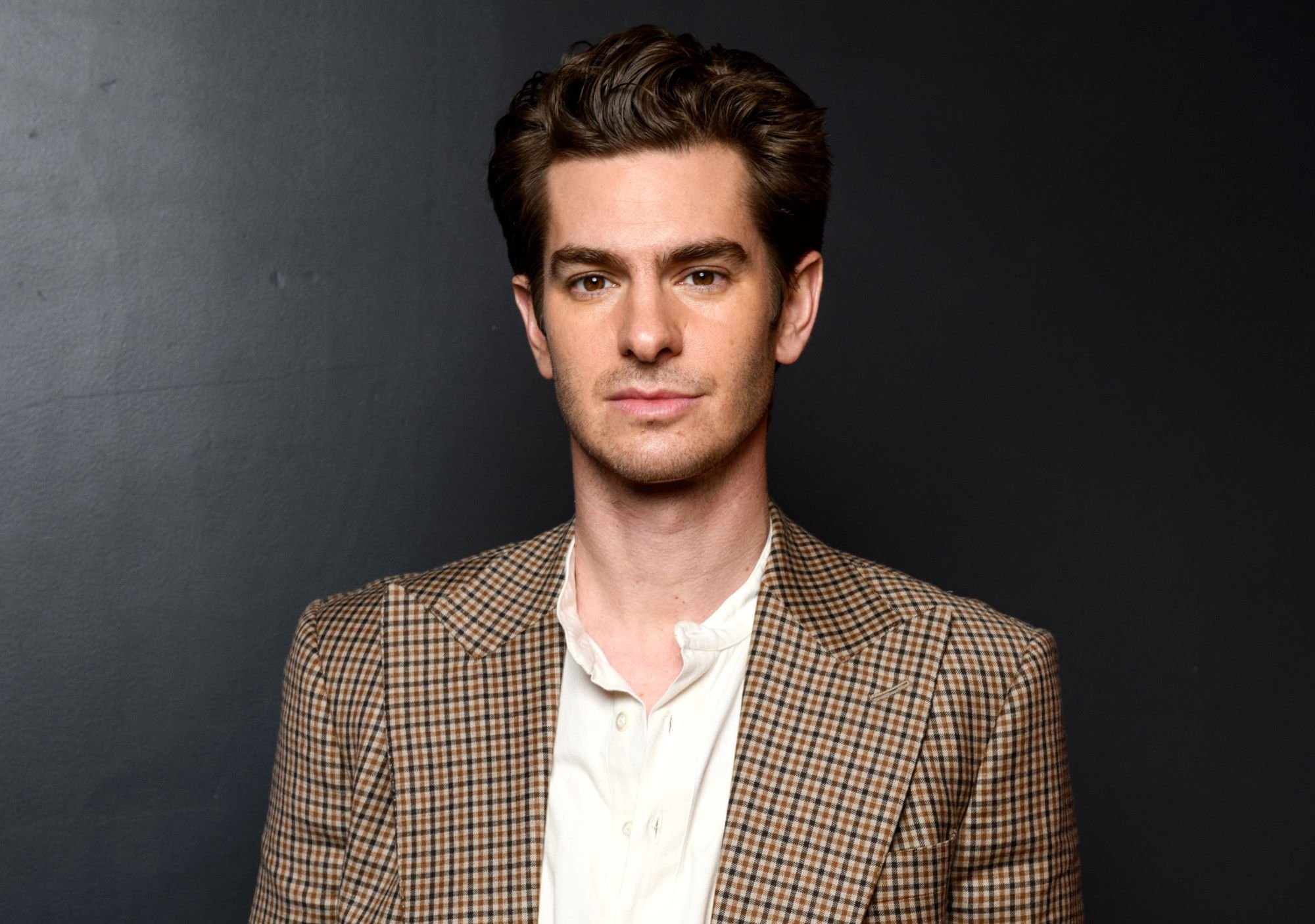 'Spider-Man: No Way Home' star Andrew Garfield wears a brown, black, and white plaid blazer over a white button-up shirt.