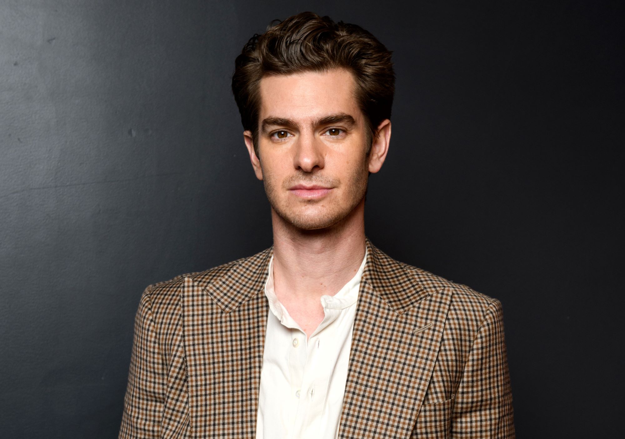 'Spider-Man: No Way Home' star Andrew Garfield wears a brown, black, and white plaid blazer over a white button-up shirt.