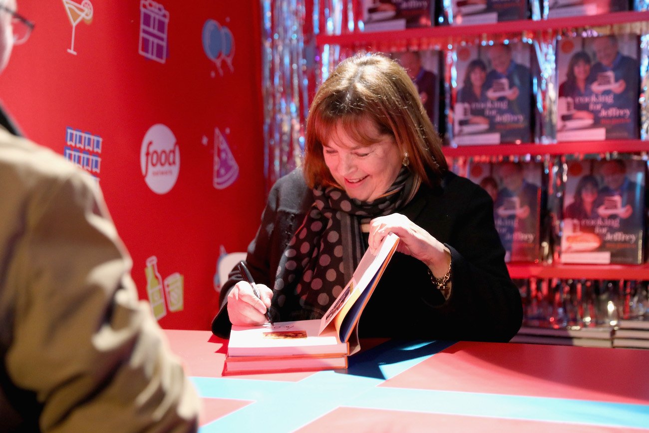 Ina Garten smiles as she signs a copy of a cookbook
