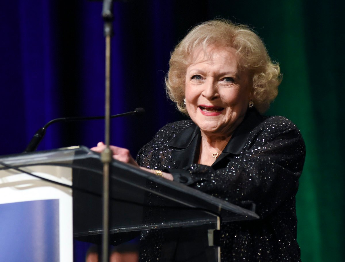 Betty White wears black and smiles at a podium