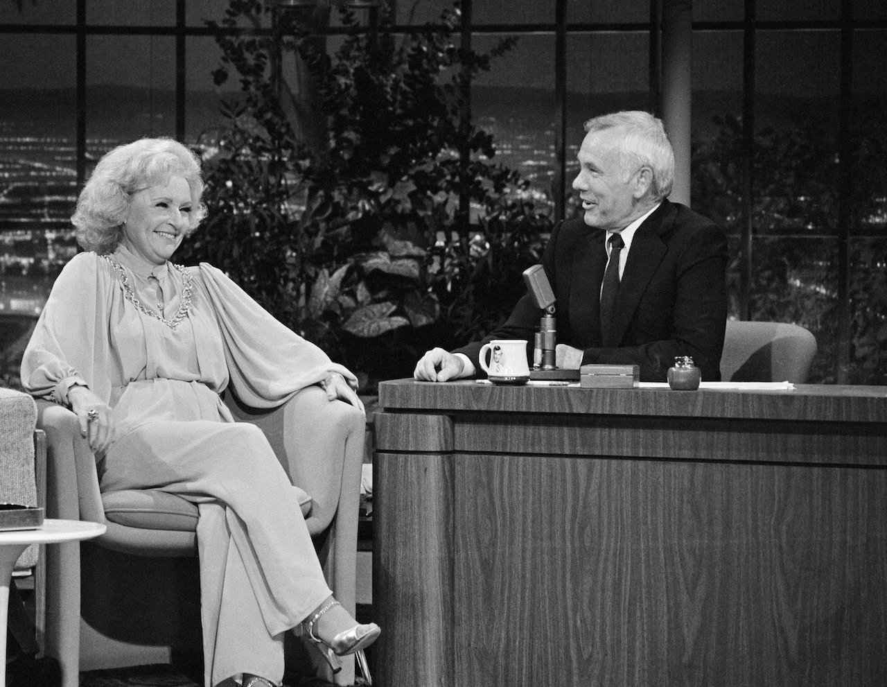 Betty White sits in the guest chair at 'The Tonight Show' with Johnny Carson behind the desk.