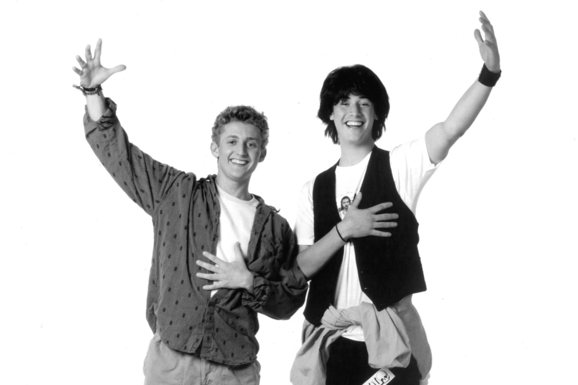 'Bill & Ted's Excellent Adventure' Alex Winter as Bill Preston and Keanu Reeves as Ted Logan holding an arm up in black-and-white photo