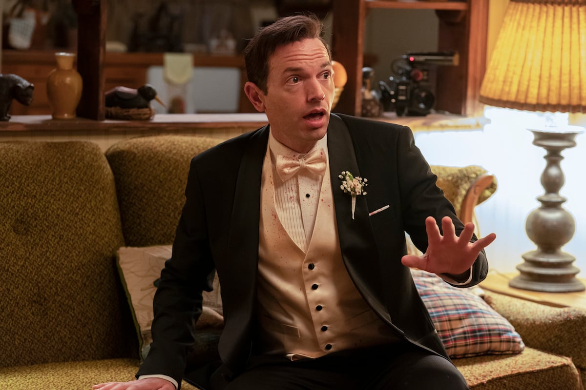 Paul Scheer as Keith, wearing a blood-spattered tux and sitting on a couch in 'Black Monday' Season 3