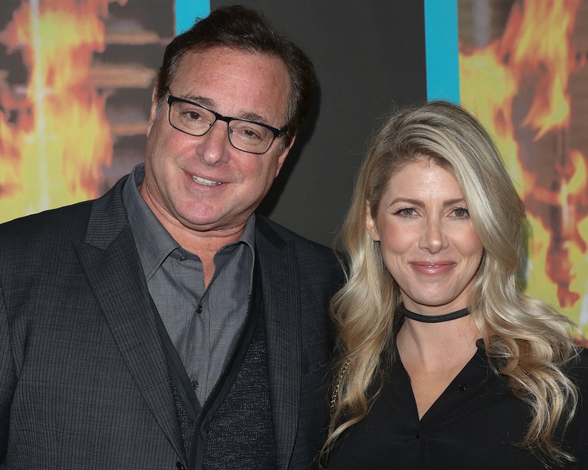 Bob Saget and Kelly Rizzo smile and pose together at an event.