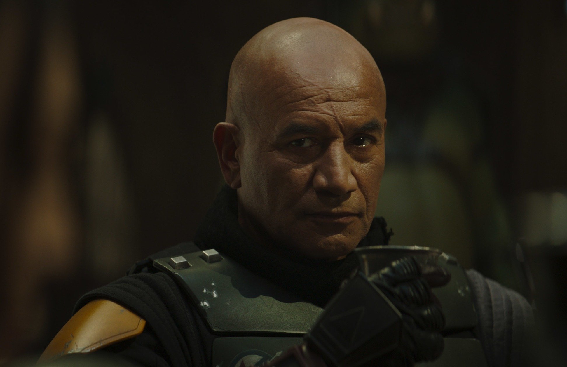 Temuera Morrison as Boba Fett in 'The Book of Boba Fett.' The room he's in is dark, and he's looking to the side of the camera.