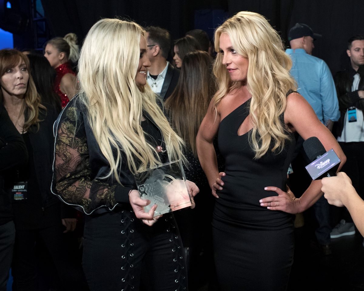 Jamie Lynn Spears and Britney Spears look at each other, both dressed in black. 