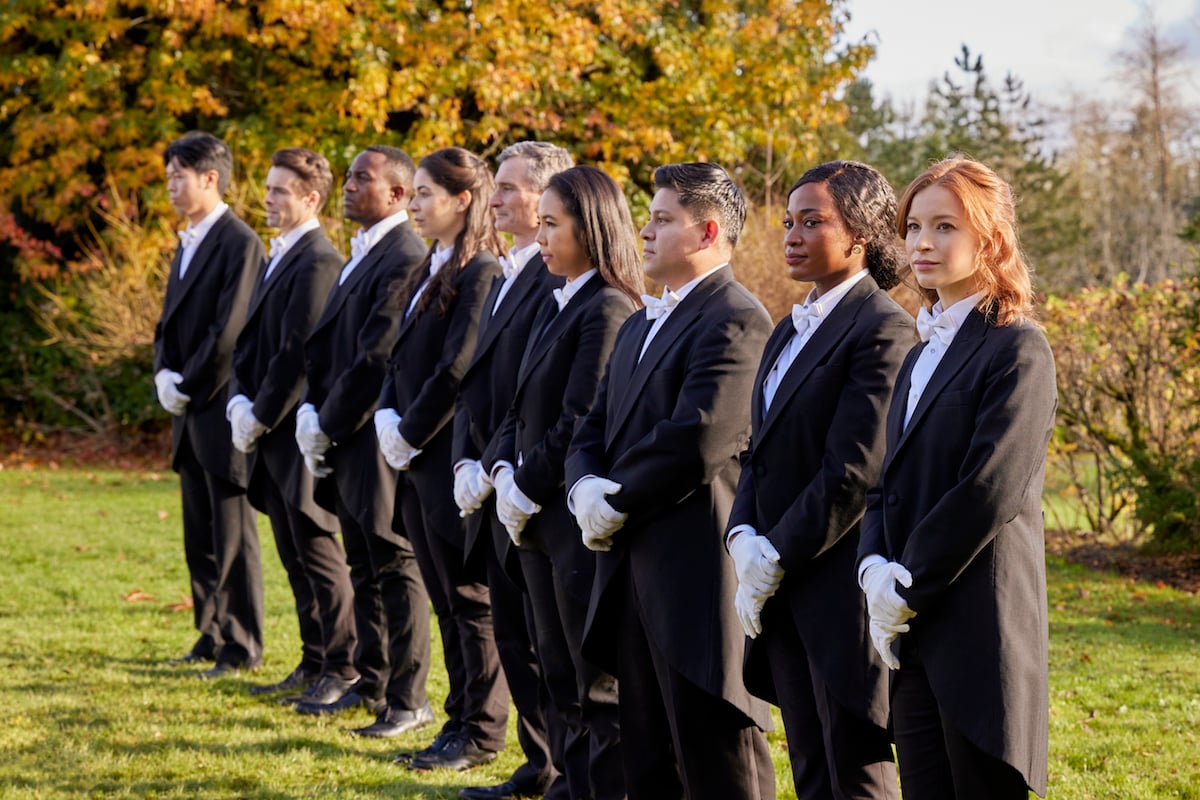 Een rij mensen gekleed in butlerkostuums in de film Hallmark 