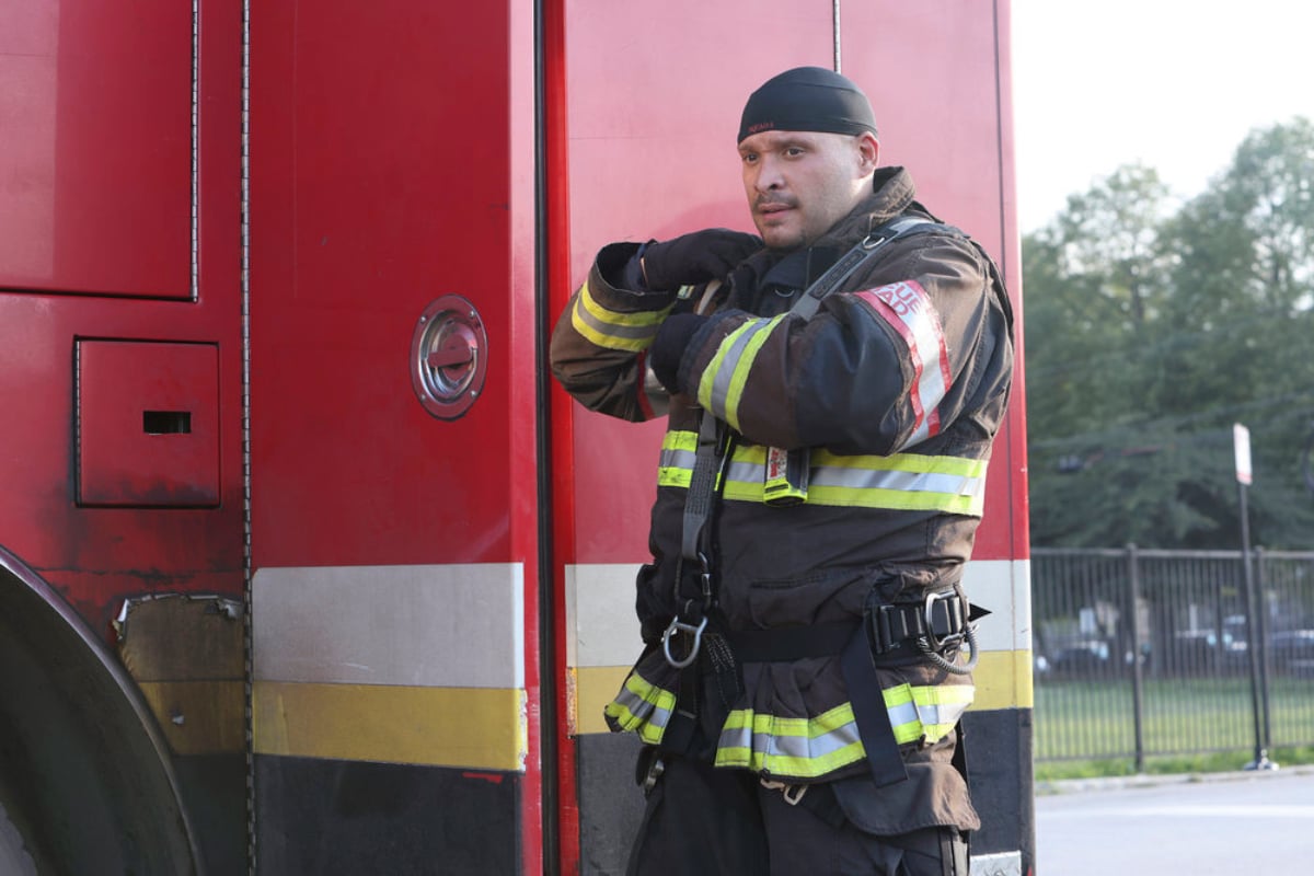 Joe Minoso as Joe Cruz in Chicago Fire. Cruz suits up in his fireman gear next to a fire truck.