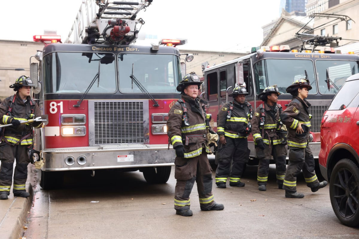 Alberto Rosende as Blake Gallo, Christian Stolte as Mouch, Daniel Kyri as Darren Ritter, and Miranda Rae Mayo as Stella Kidd in Chicago Fire Season 10. The crew of Truck 81 stand near two fire trucks. 