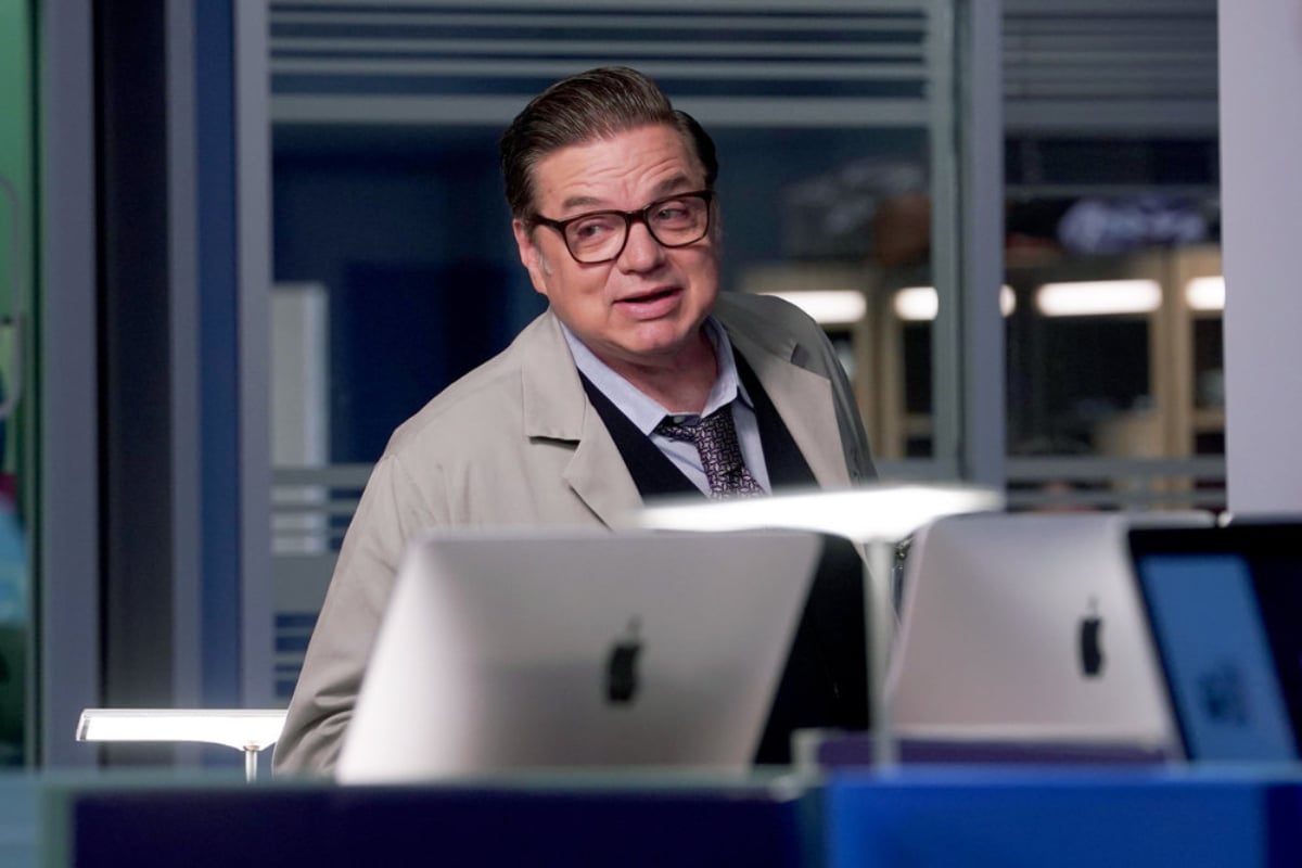 Oliver Platt as Daniel Charles in Chicago Med Season 7. Dr. Charles smiles. There are computers in front of him.