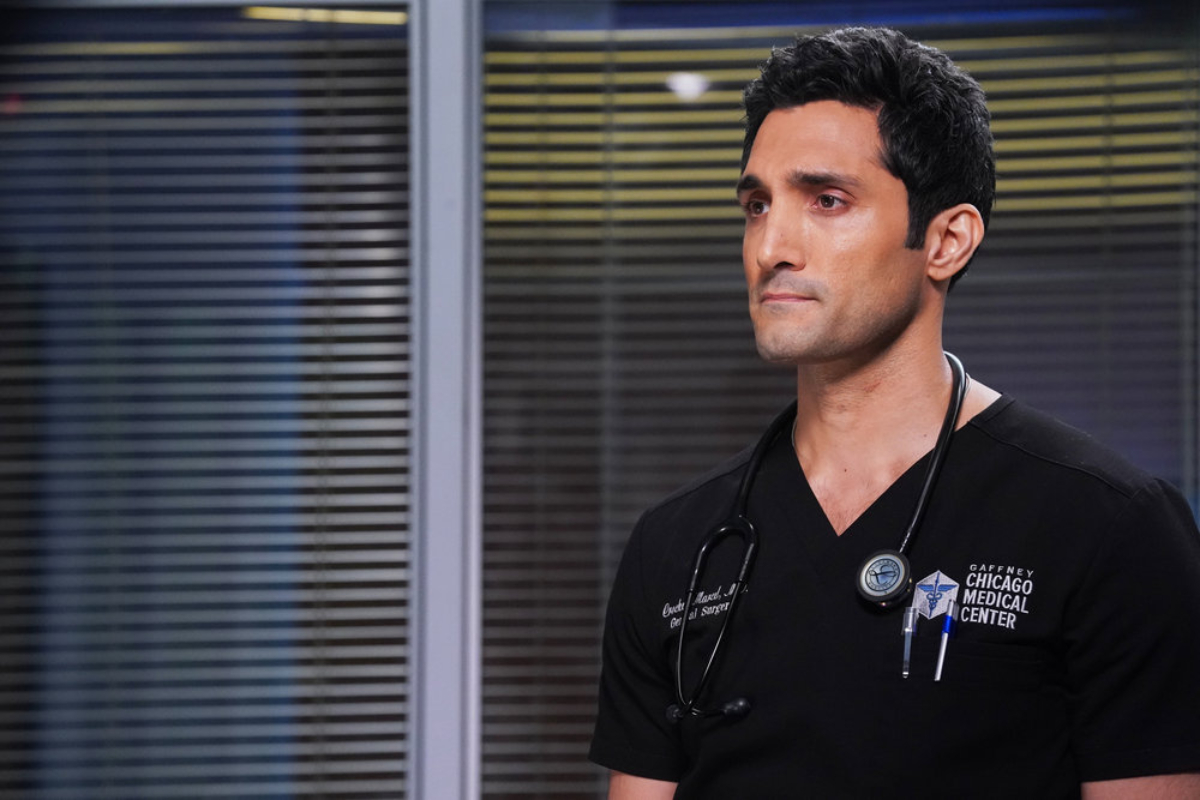 Dominic Rains as Crockett Marcel in Chicago Med Season 7. Crockett wears hospital scrubs and looks concerned.