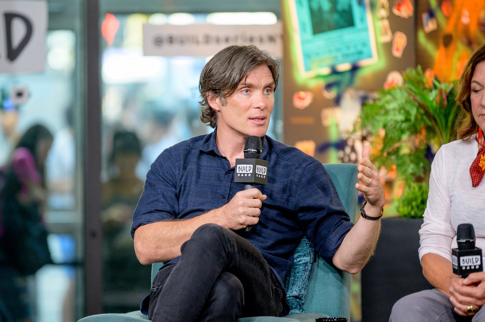 Cillian Murphy from 'Peaky Blinders' Season 6 sitting in a chair talking into a microphone during an interview