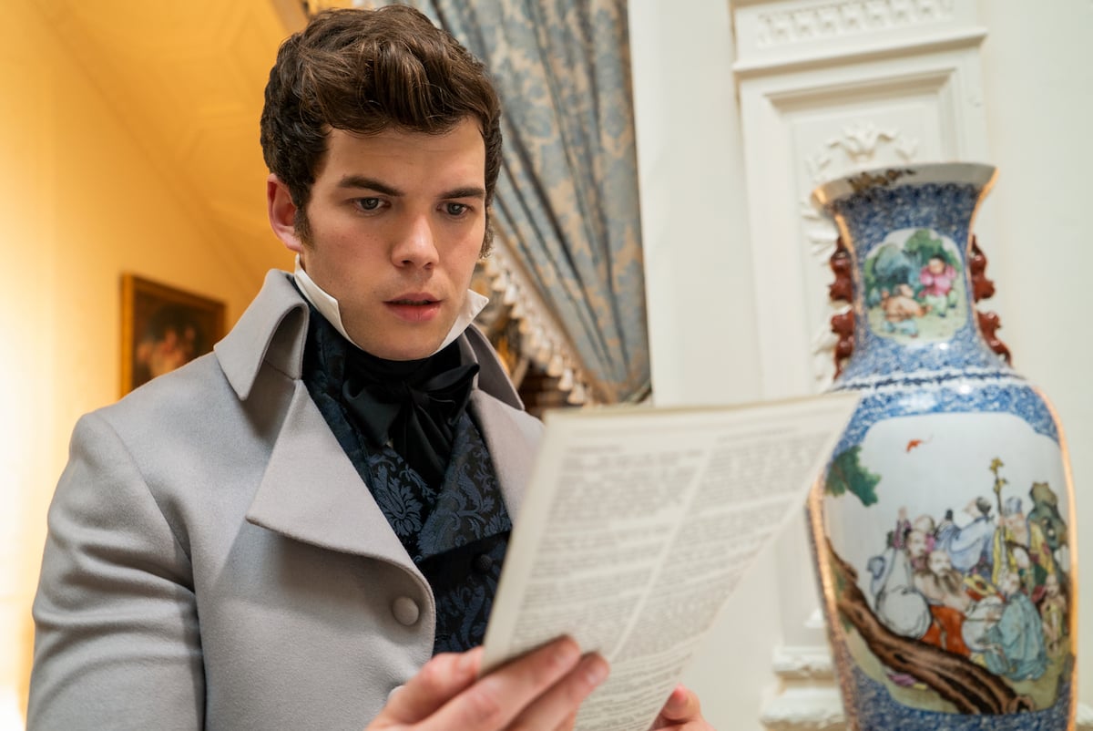 Luke Newton as Colin Bridgerton reading Lady Whistledown's Society Papers in 'Bridgerton' Season 1