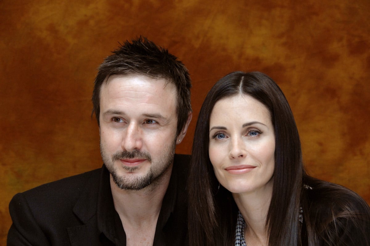 David Arquette and Courtney Cox smiling in front of an orange textured background