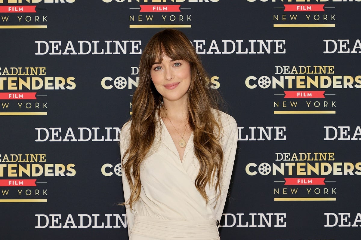 Dakota Johnson smiling in a white dress.