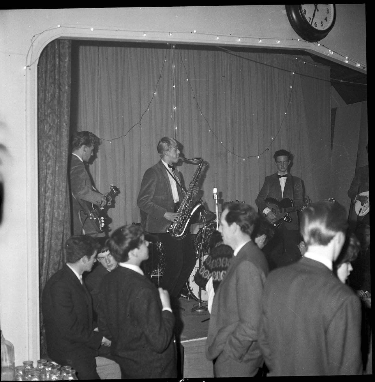 David Bowie playing saxophone and wearing a suit on stage in England, 1963.