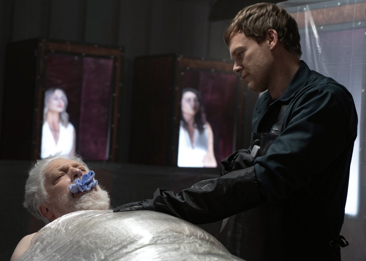 Clancy Brown as Kurt and Michael C. Hall as Dexter in Dexter: New Blood. Kurt is wrapped to a kill table while Dexter stands next to him. Kurt's victims can be seen preserved and dressed in white in the background.