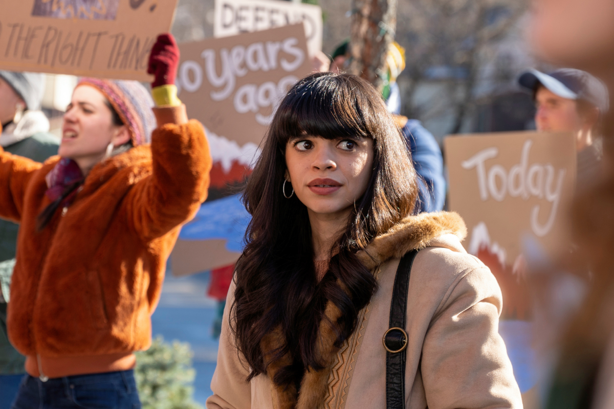 Gizel Jimenez as Tess in Dexter: New Blood. Tess stands in front of a bunch of protesters carrying signs.