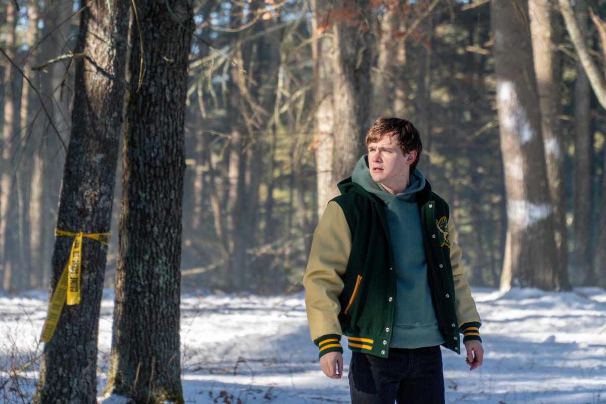 Jack Alcott as Harrison in Dexter: New Blood. Harrison stands in the snowy woods weary a letterman jacket.